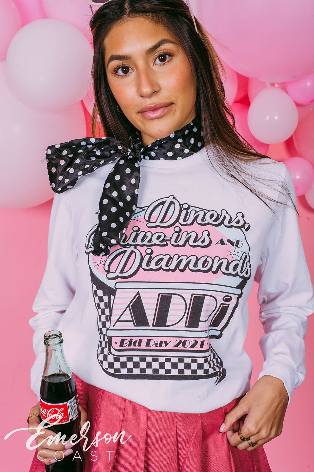 Girl wears white long sleeve that reads "Diners, Drive-ins, and Diamonds. ADPi Bid Day."